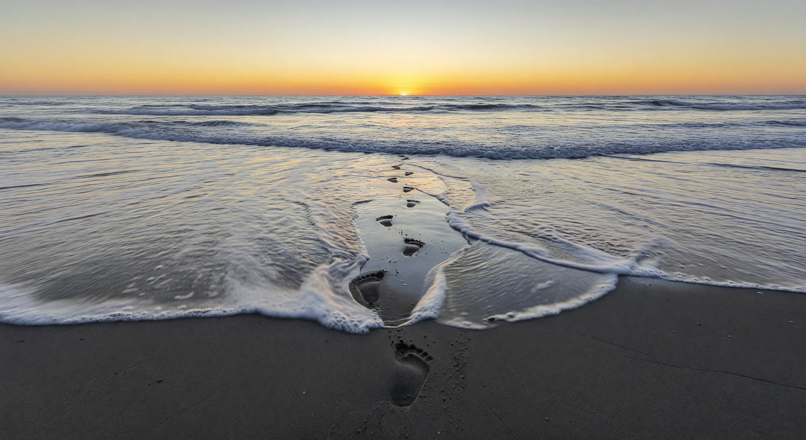 Footprints on dawn beach
